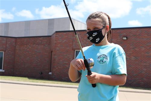 Student wearing a mask while casting a reel 